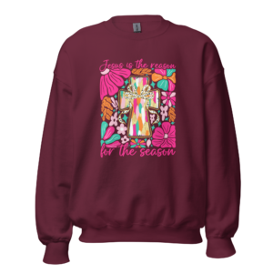 'Jesus is the Reason' Crewneck is a Women's crew neck sweatshirt with a pink cross and flowers design and the message 'Jesus is the Reason for the Season,' available in black, navy, maroon, forest green, dark heather grey, royal blue, light blue, sport grey, light pink, ash grey, and white. Made from a soft 50/50 cotton-polyester blend, perfect for the holiday season.